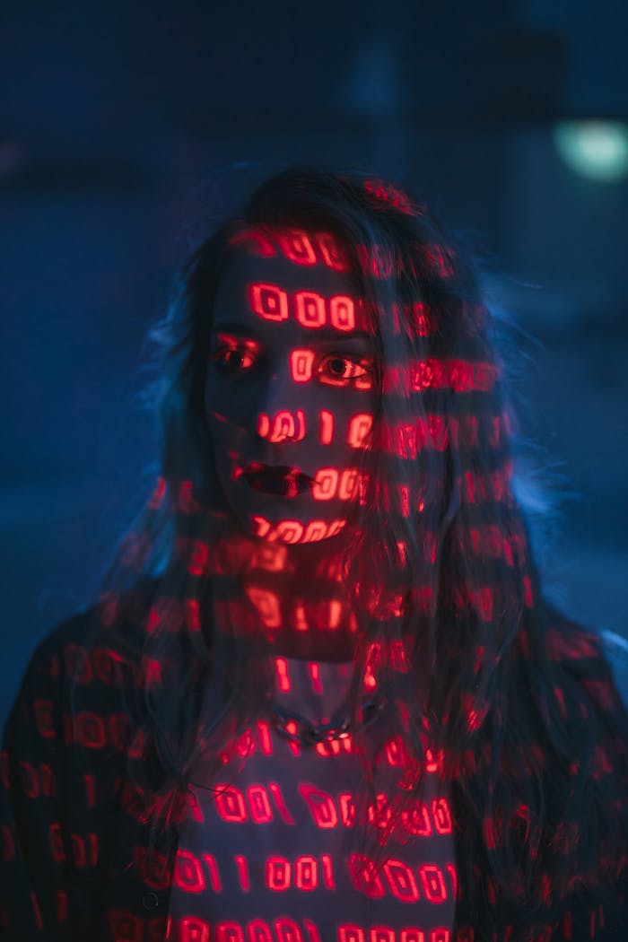 A woman with red binary code projected on her face, signifying technology and cybersecurity.